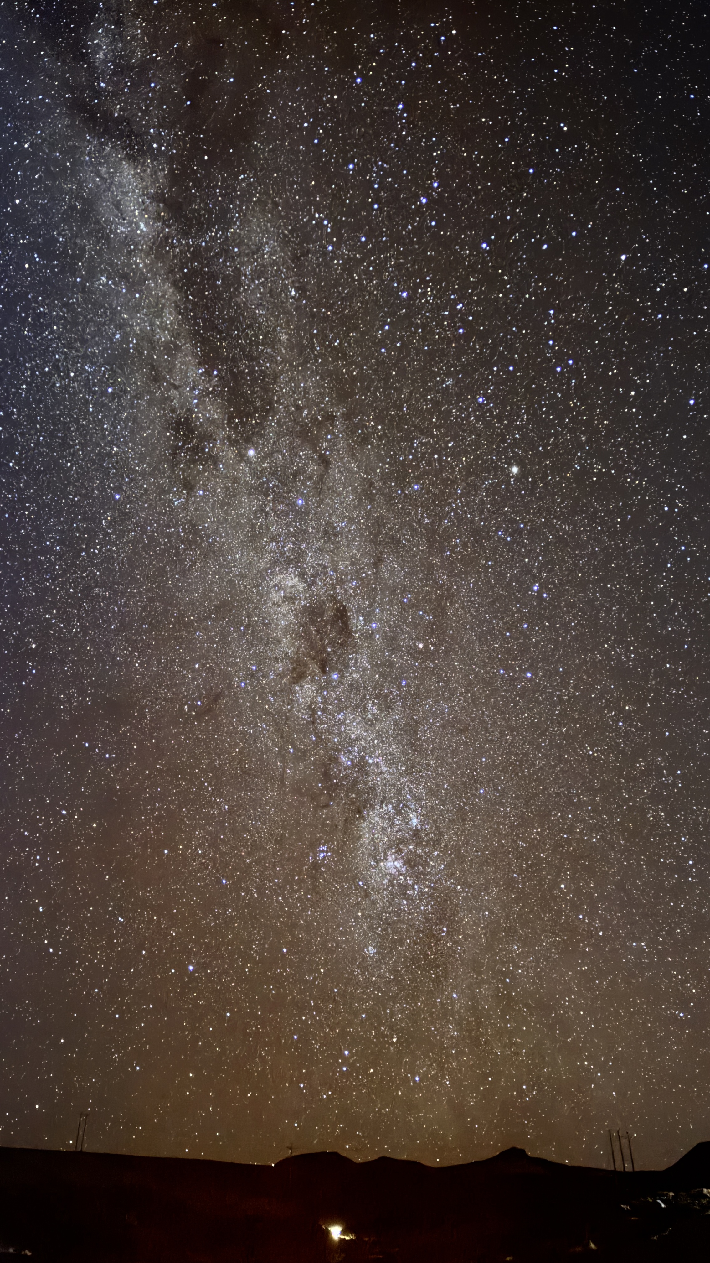 Brilliant Milky Way galaxy stretching across dark night sky above mountain silhouettes