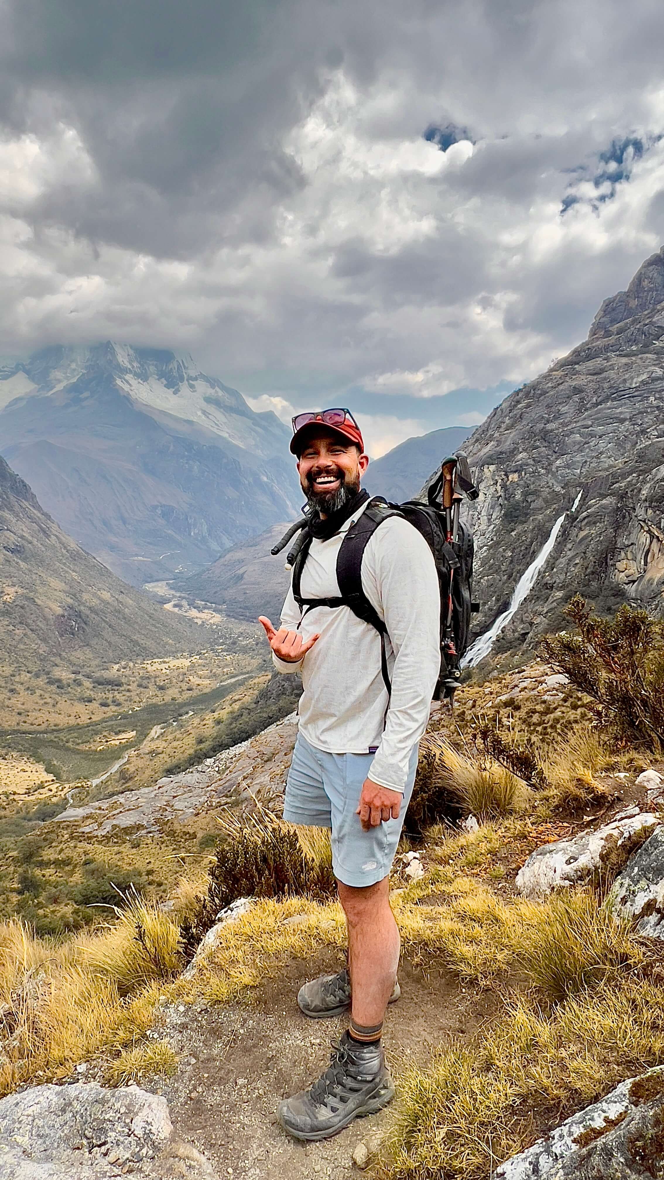 Hiker standing on mountain trail with dramatic valley and peaks behind